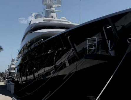 Close up of a yacht's black hull with clear sky in the background.