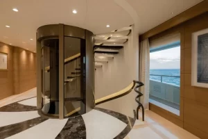 Glass elevator inside a superyacht with a spiral staircase