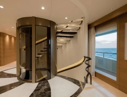 Glass elevator inside a superyacht with a spiral staircase