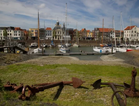 Vlissingen's old harbour with boats and small yachts docked in front of a row of houses.